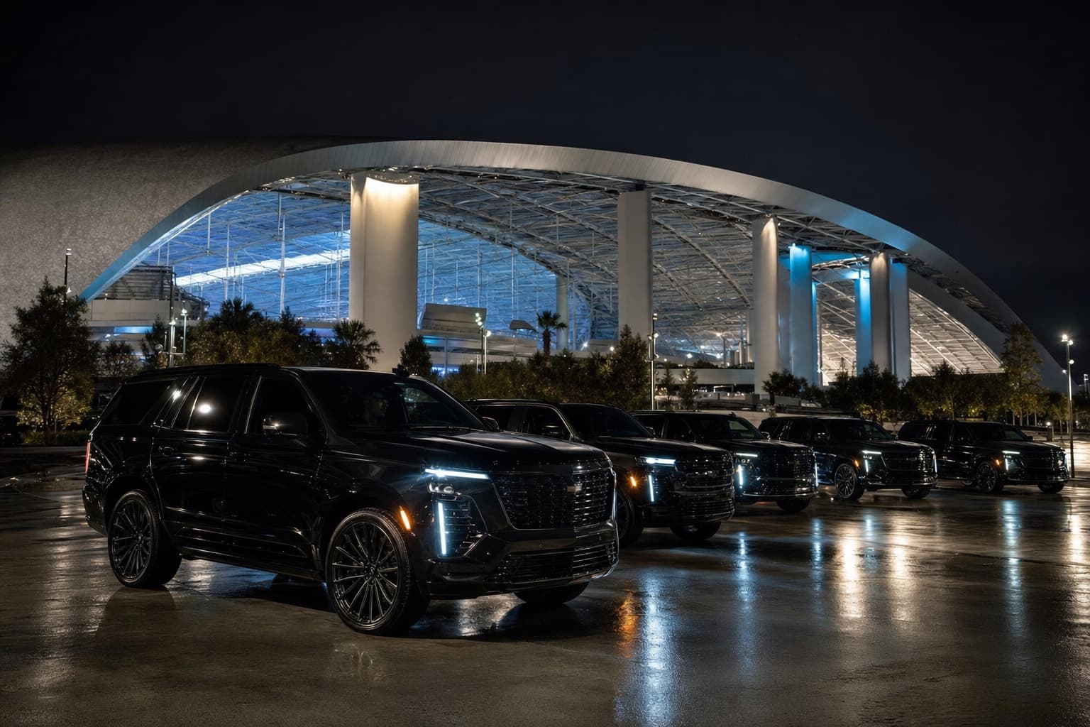 Multiple luxury SUVs staged outside SoFi Stadium at night